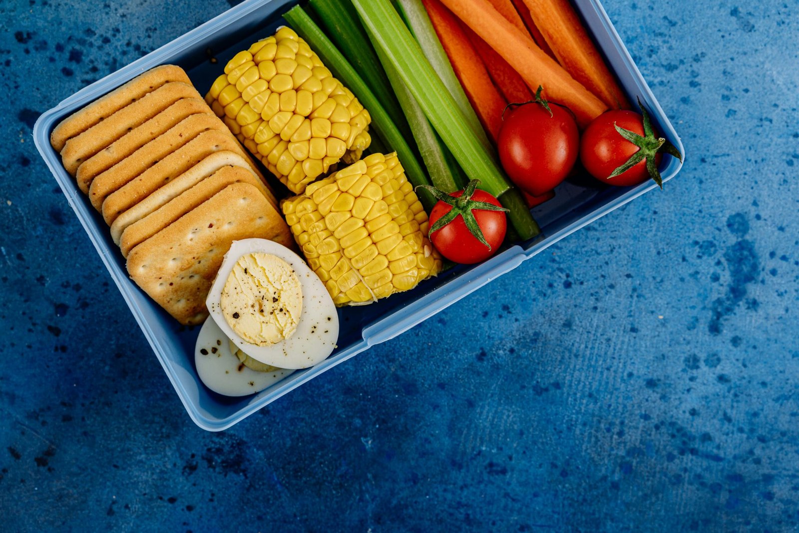 A vibrant lunchbox filled with nutritious vegetables, eggs, and crackers for a healthy meal.
