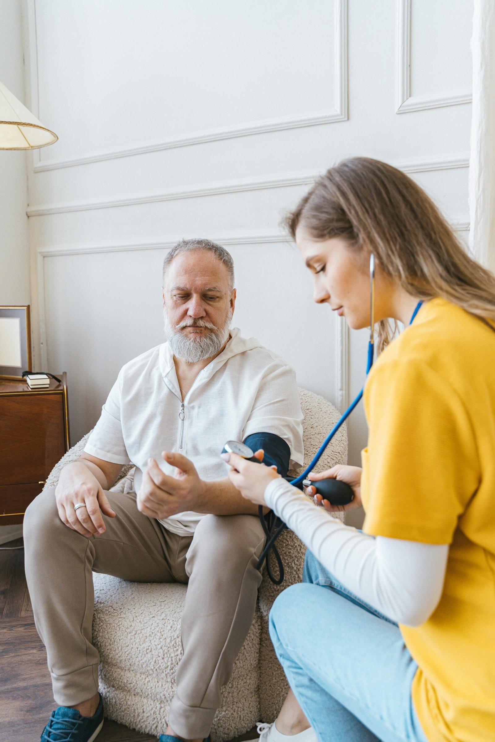 A healthcare professional checks an elderly man's blood pressure in a cozy room.